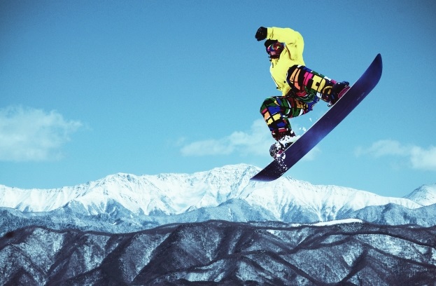雪山をスノボーでジャンプする男性